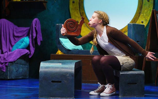 Performer interacting with a snail prop during "The Snail and the Whale" stage show.