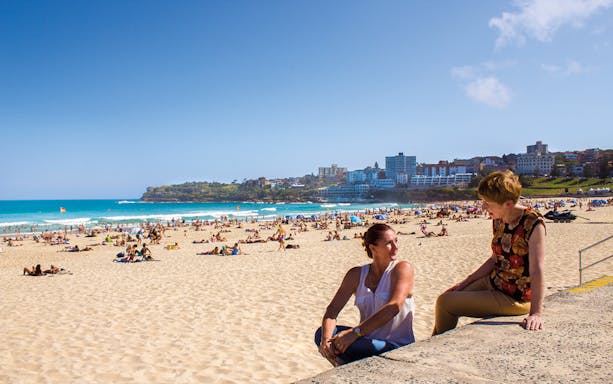 People relaxing on Bondi Beach with Sydney skyline in the background.