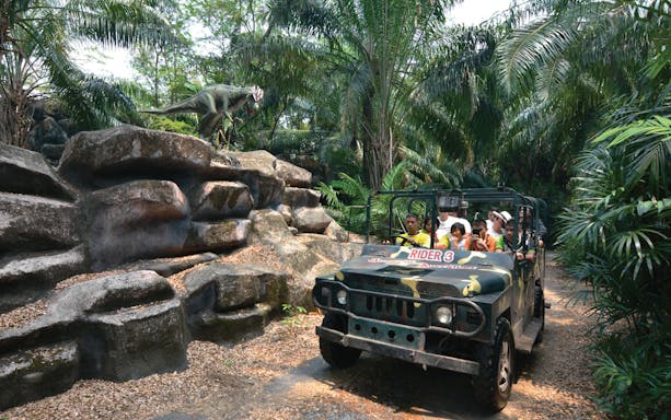 Jeep tour through jungle with dinosaur statue at Siam Park City, Bangkok.