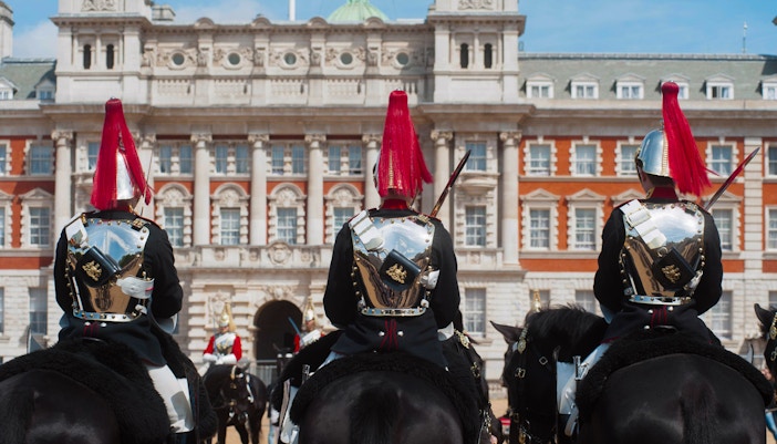 Guards on horseback in ceremonial attire outside Buckingham Palace, London.