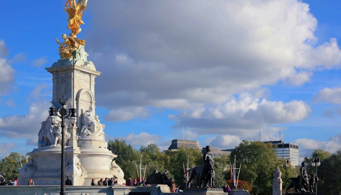 Victoria Memorial near Buckingham Palace, London, with tourists gathered around.