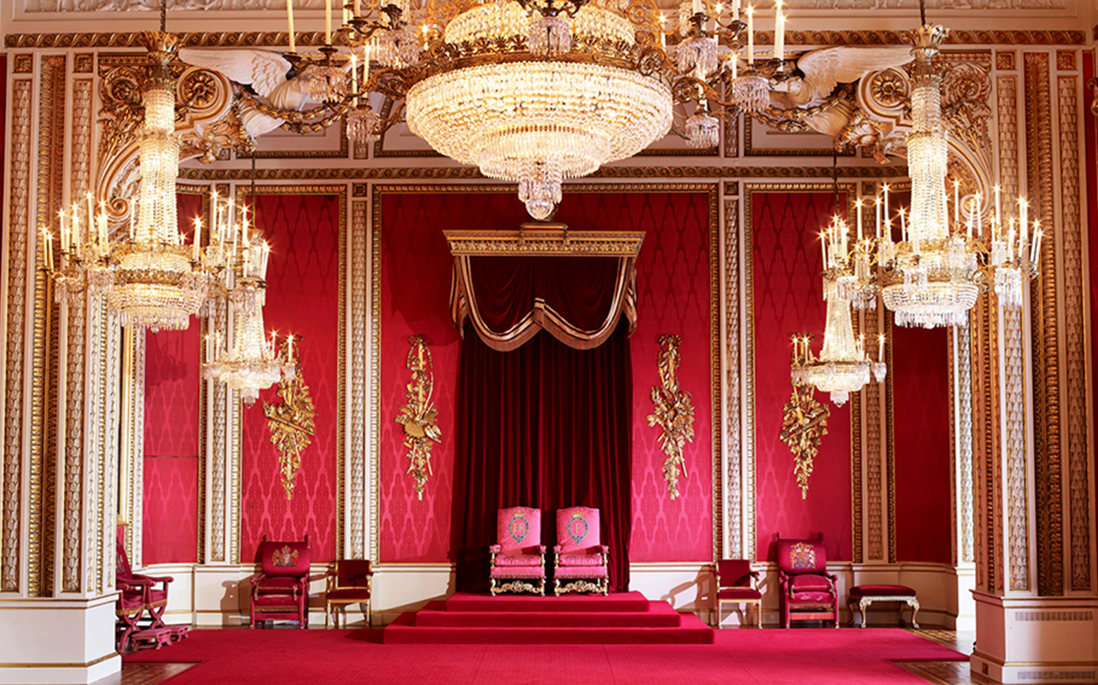 Buckingham Palace State Rooms with ornate chandeliers and red decor.