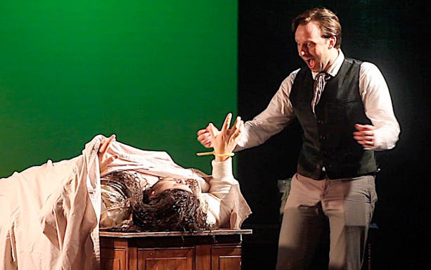 Man reacting to a figure rising from a table, inspired by Frankenstein.