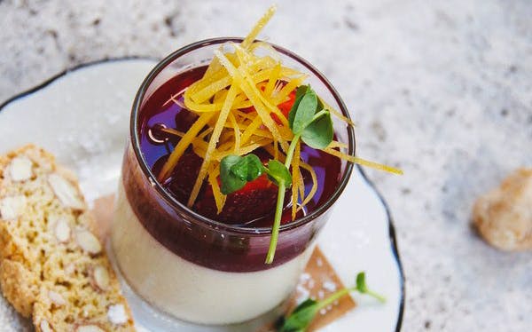 Glass of dessert with berry sauce and citrus zest, served with biscotti on Wynwood Food & Art Tour.