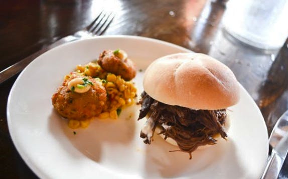 Pulled beef sandwich and corn fritters on a plate during Wynwood Food & Art Tour.