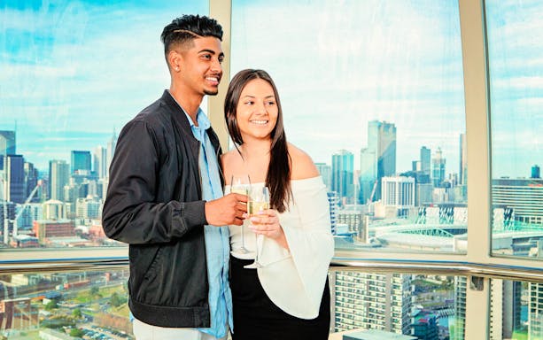 Couple enjoying view from Melbourne Star Observation Wheel with city skyline.