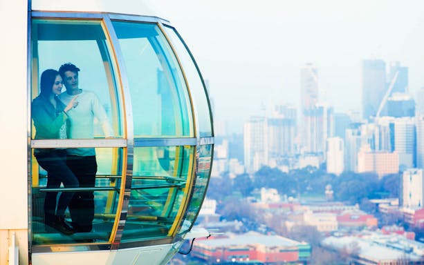 Couple enjoying view from Melbourne Star Observation Wheel with city skyline.