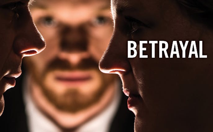 Close-up of two faces with a third person blurred in the background, representing betrayal.