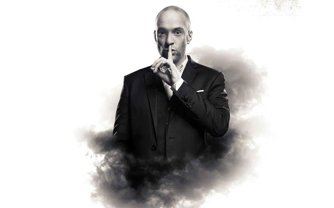 Man in a suit with finger to lips, surrounded by smoke, related to Derren Brown: Secret.