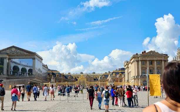 Visitors exploring the Hall of Mirrors in Versailles Palace during a guided tour.