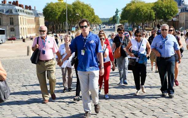 Visitors exploring the ornate gardens of Versailles Palace, France, during a guided tour.
