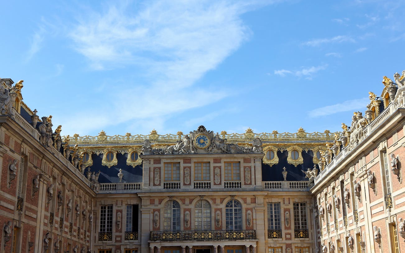 Versailles Palace exterior with tourists in line for guided tour of gardens.