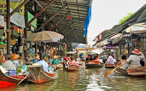 Boats navigating Damnoen Saduak Floating Market in Thailand.