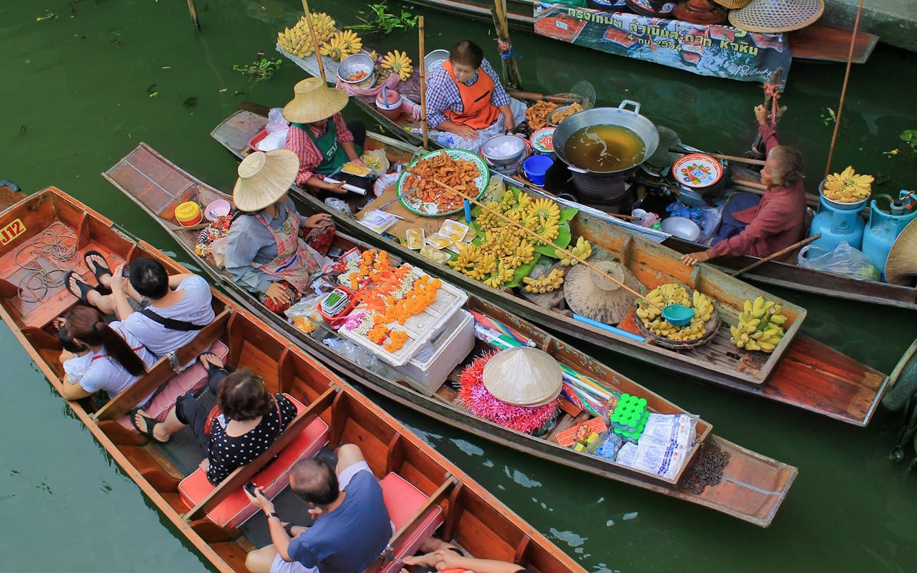 Small boats with vendors selling fruits and snacks at Damnoensaduak Floating Market, Thailand.