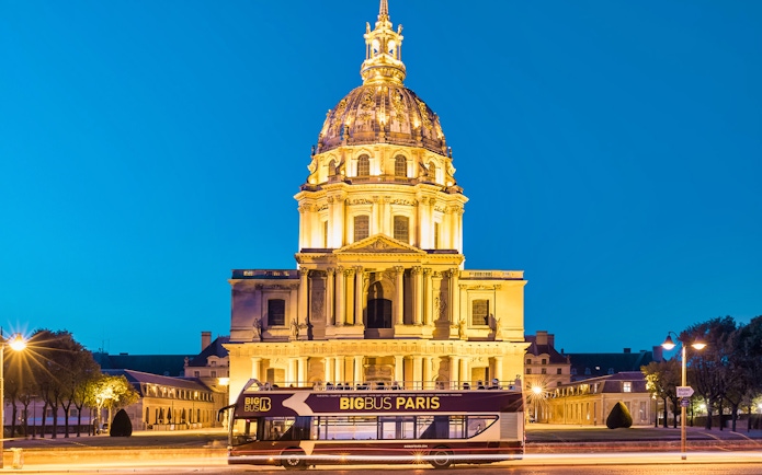 Big Bus tour passing Les Invalides at night in Paris.