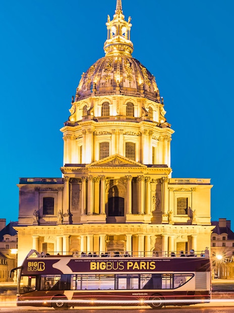 Big Bus tour passing Les Invalides at night in Paris.