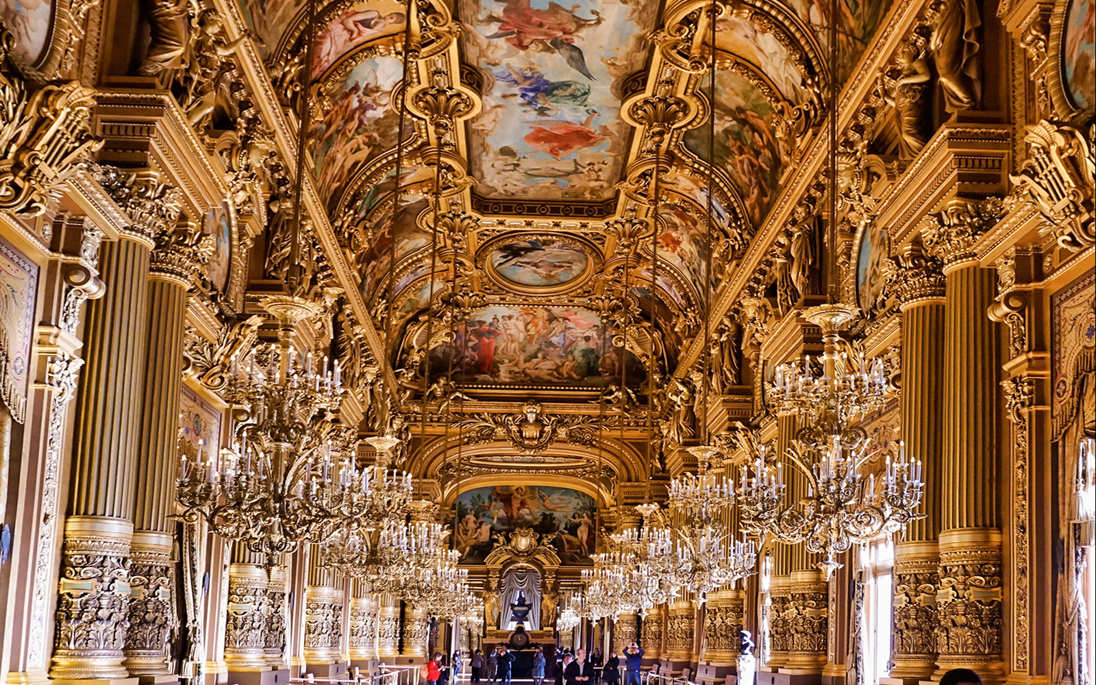 Ornate interior of Opera Garnier with chandeliers and painted ceiling, Paris.