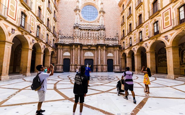 Visitors exploring the courtyard of Montserrat Monastery during a guided tour.