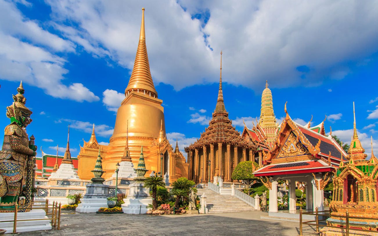 Ayutthaya temples with golden spires and ornate structures under a blue sky.