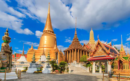 Ayutthaya temples with golden spires and ornate structures under a blue sky.