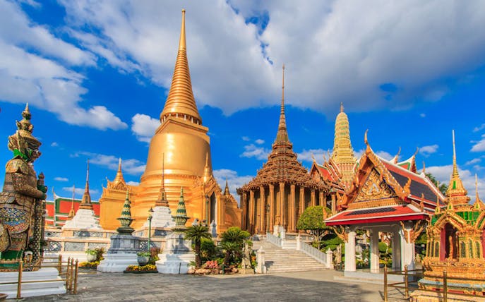 Ayutthaya temples with golden spires and ornate structures under a blue sky.