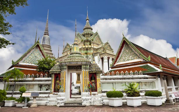 Wat Arun temple complex in Bangkok with ornate spires and colorful architecture.
