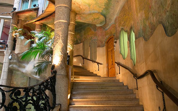 Staircase with ornate columns and colorful ceiling in La Pedrera, Barcelona.