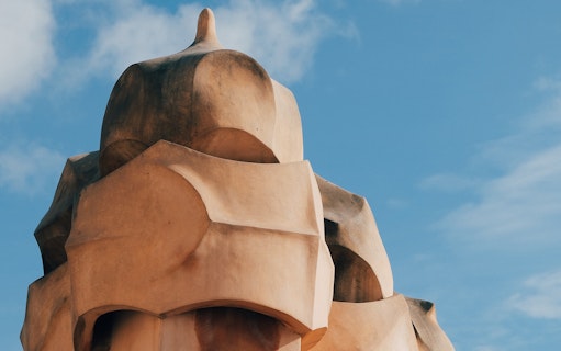 Chimney detail of La Pedrera in Barcelona under a blue sky.
