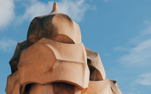 Chimney detail of La Pedrera in Barcelona under a blue sky.