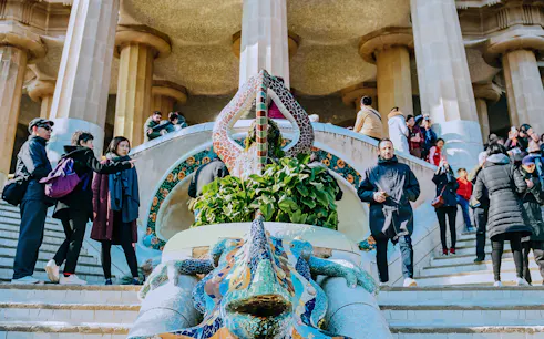 Visitors at Park Güell's mosaic lizard fountain, Barcelona, during guided tour.