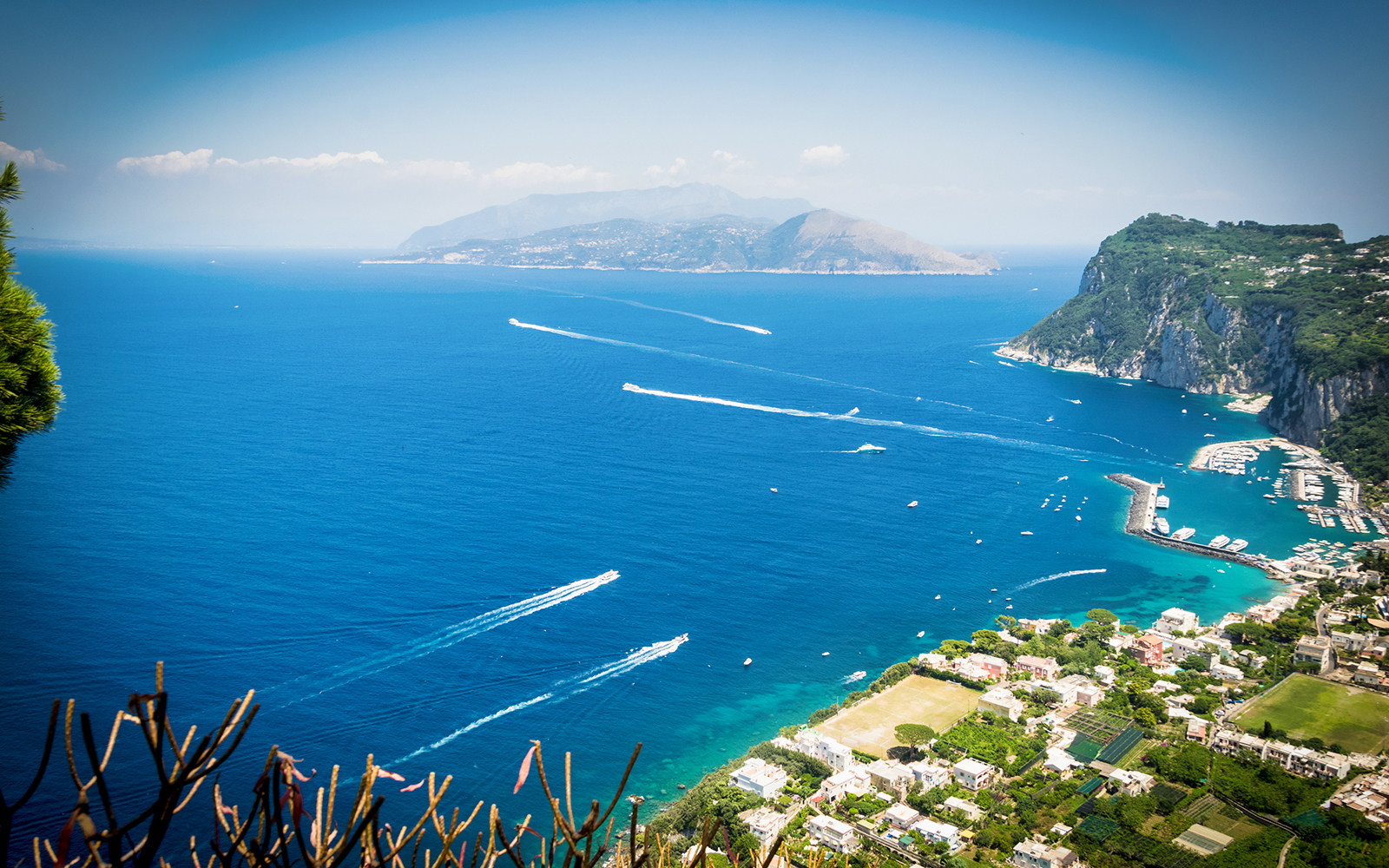 Aerial view of Amalfi Coast with boats on the blue sea and coastal cliffs.