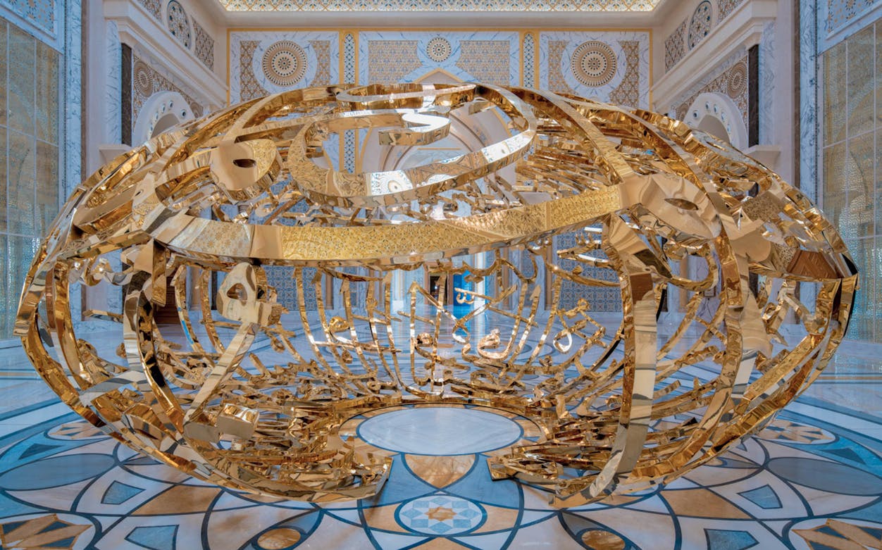 Golden sculpture inside Qasr Al Watan, Abu Dhabi, with intricate Arabic calligraphy.