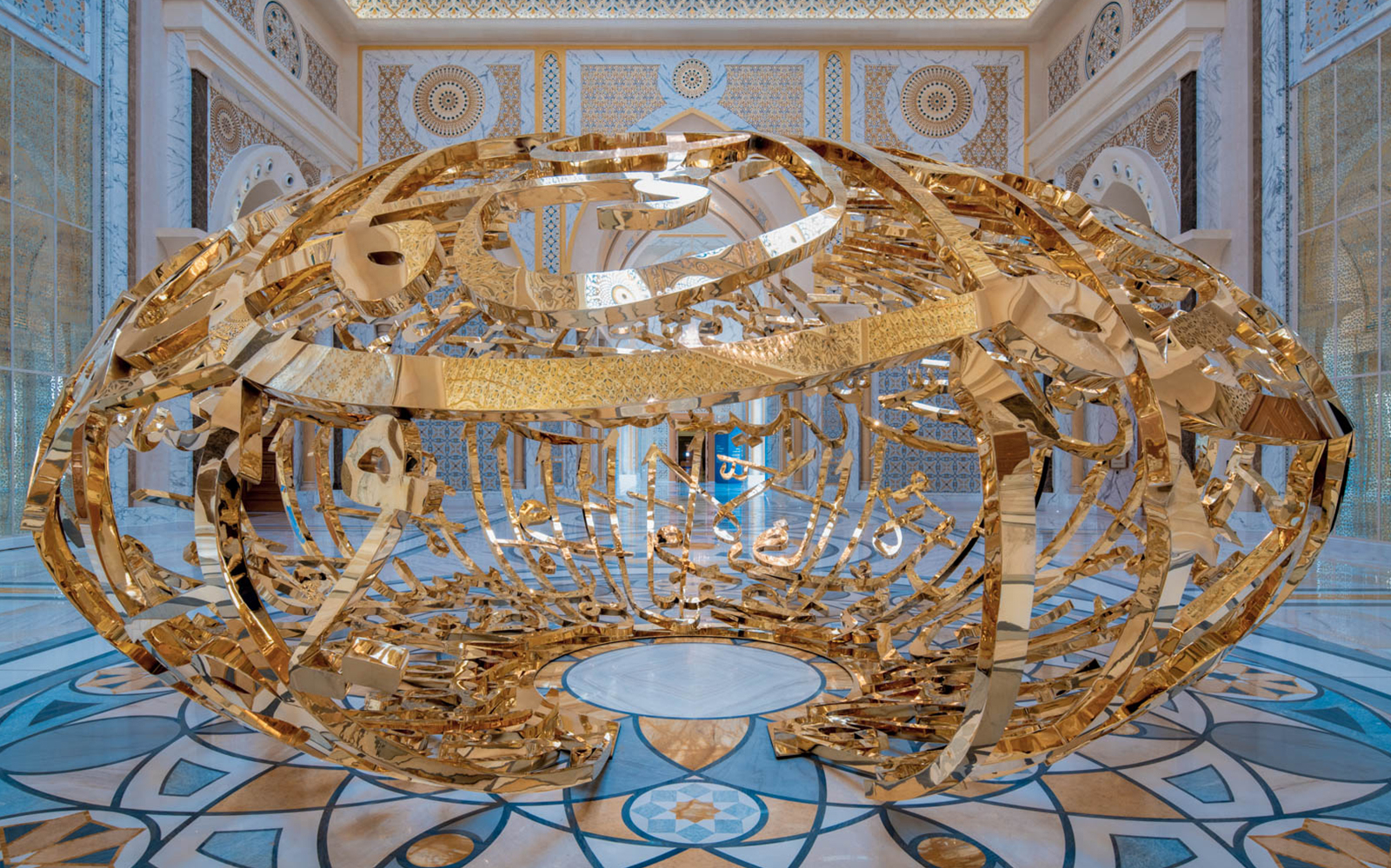 Golden sculpture inside Qasr Al Watan, Abu Dhabi, with intricate Arabic calligraphy.