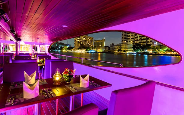Dining area on Wonderful Pearl Luxury Cruise with city skyline view at night.