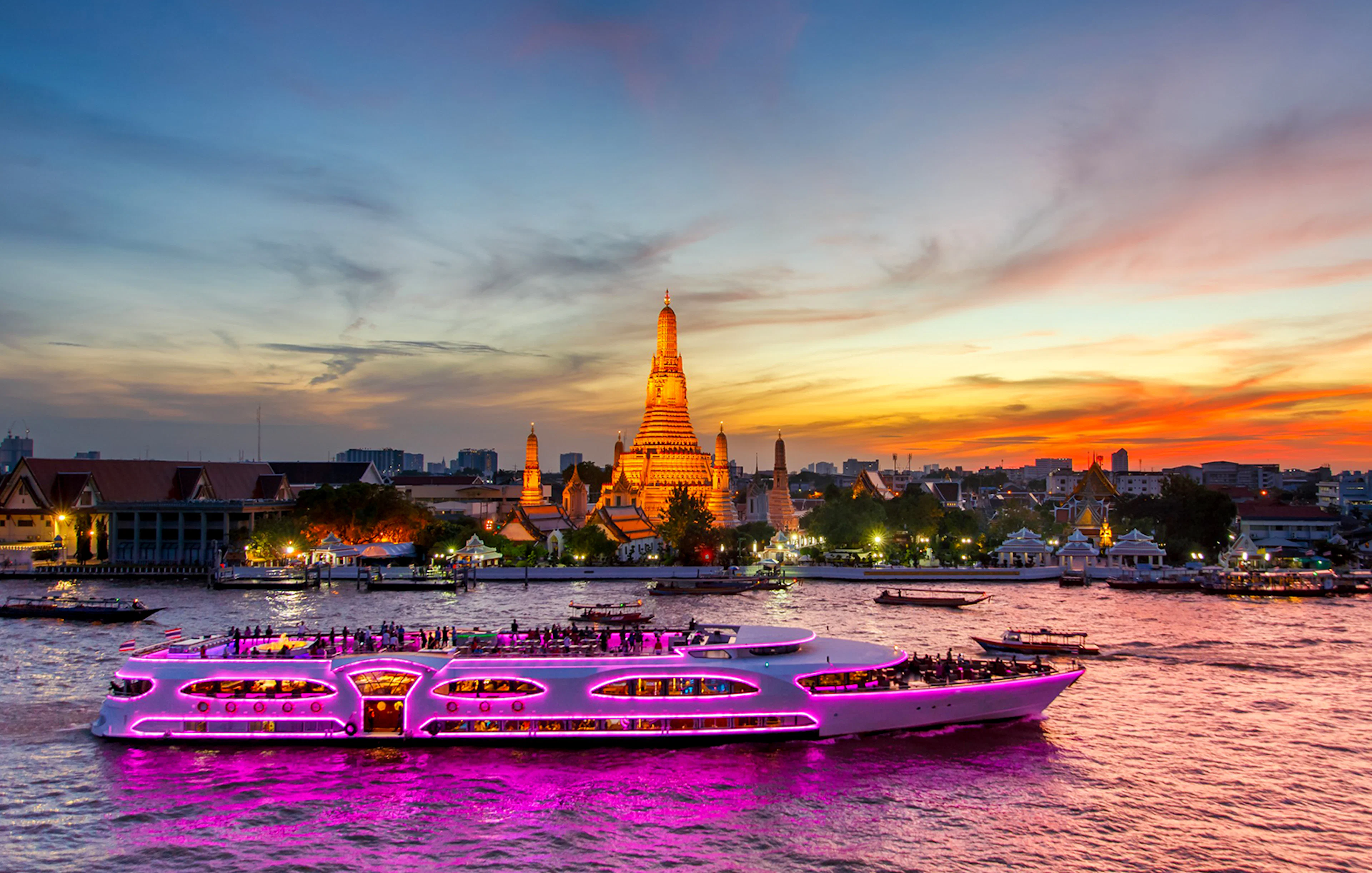 Cruise ship on Chao Phraya River at sunset near Wat Arun, Bangkok.