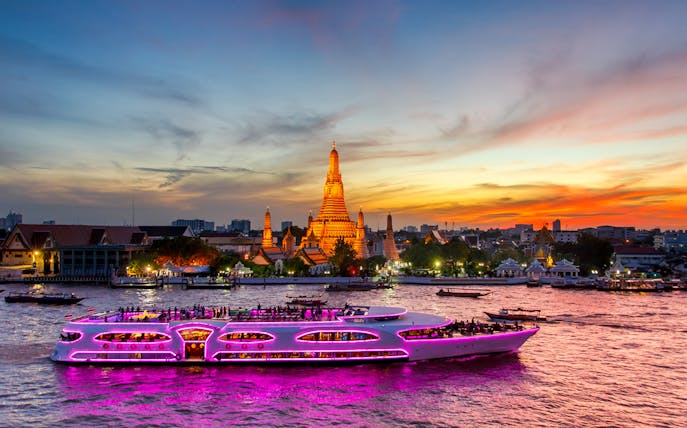 Cruise ship on Chao Phraya River at sunset near Wat Arun, Bangkok.