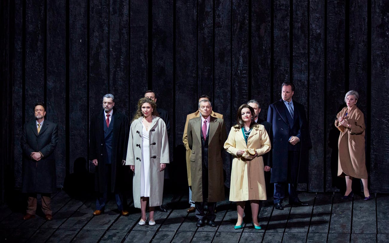 Group of actors in trench coats on stage during a performance of "Lear".