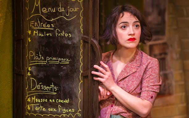 Performer in "Amelie The Musical" peeking from behind a menu board.