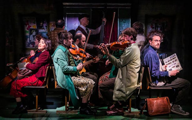 Cast of Amelie The Musical performing with instruments on stage.