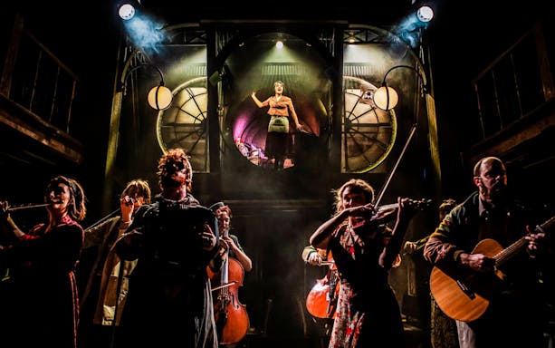 Cast performing on stage in "Amelie The Musical" with musicians and a central character.