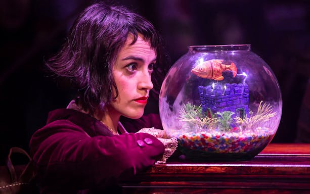 Woman gazing at fishbowl with toy fish in Amelie The Musical scene.