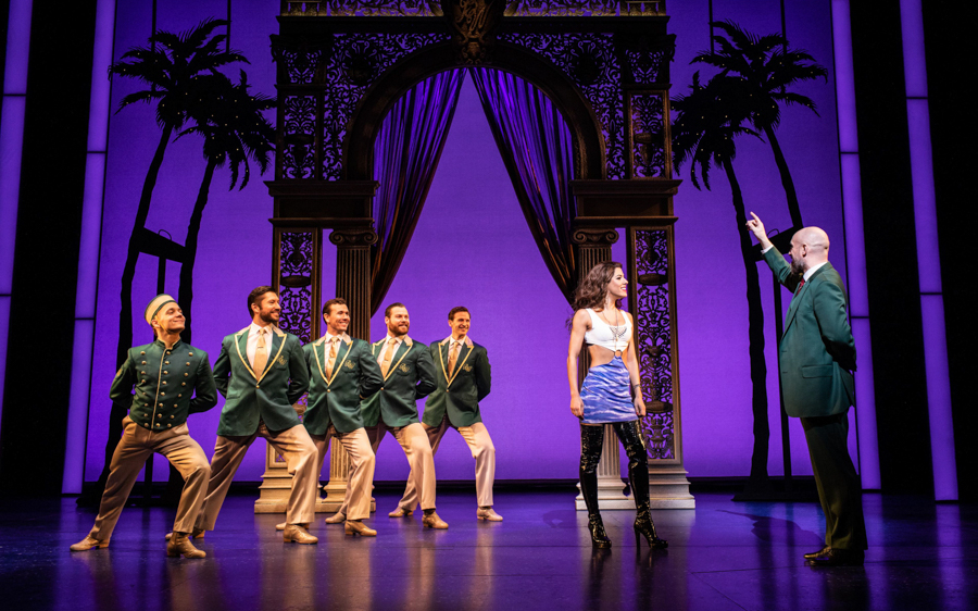 Stage performance of "Pretty Woman" musical with actors in formal attire.