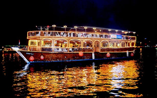 Dhow cruise with lights on Dubai Creek at night.