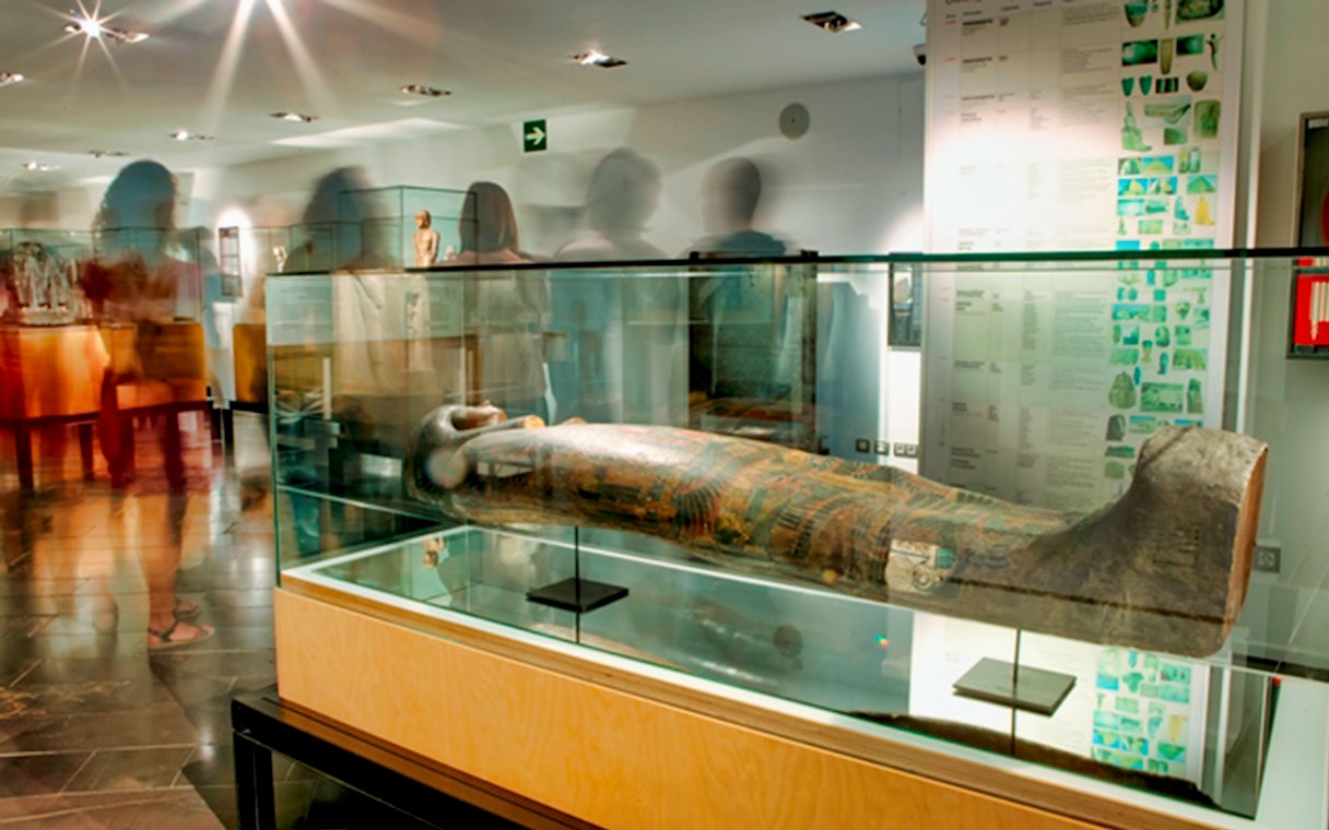 Sarcophagus display at the Egyptian Museum with visitors in the background.