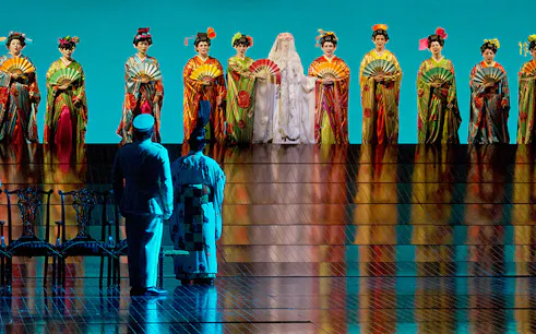 Performers in traditional attire on stage during Madama Butterfly opera.