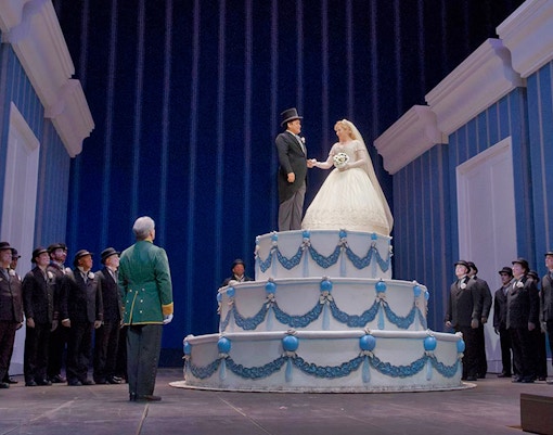 Opera scene from La Cenerentola with performers on a large cake stage.