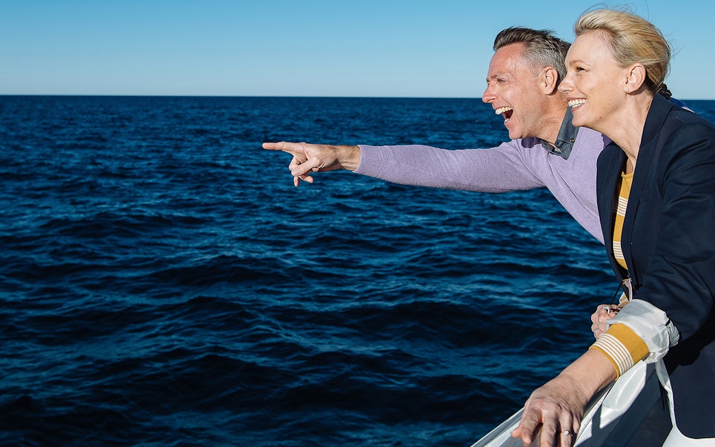 Couple pointing at whales during a Sydney whale watching cruise.