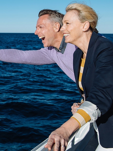 Couple pointing at whales during a Sydney whale watching cruise.