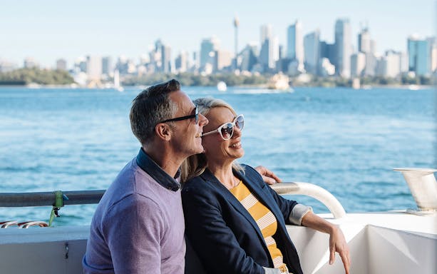 Couple enjoying a whale watching cruise with Sydney skyline in the background.