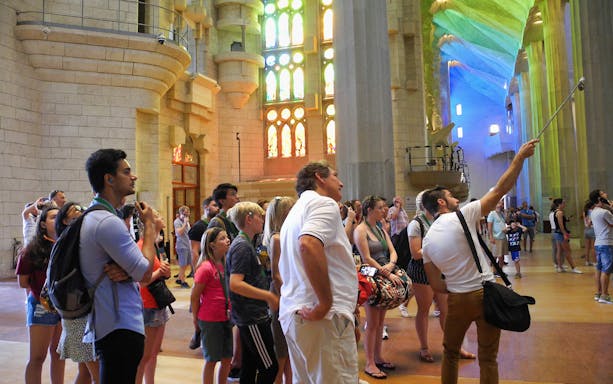 Tour group inside Sagrada Familia, Barcelona, admiring stained glass windows.